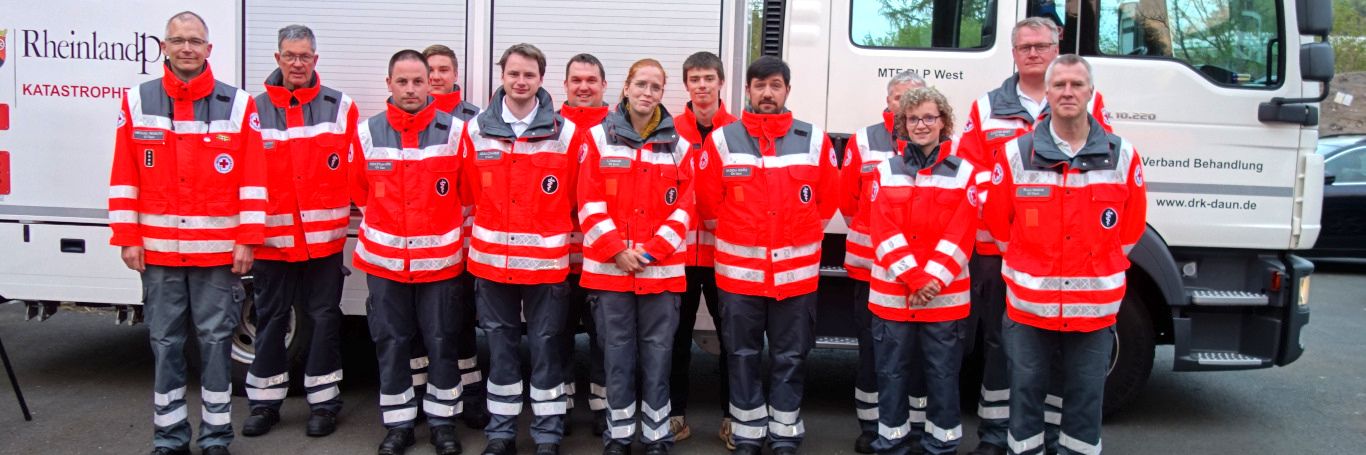 Eine Gruppe von Helfern steht vor einem Einsatzfahrzeug.