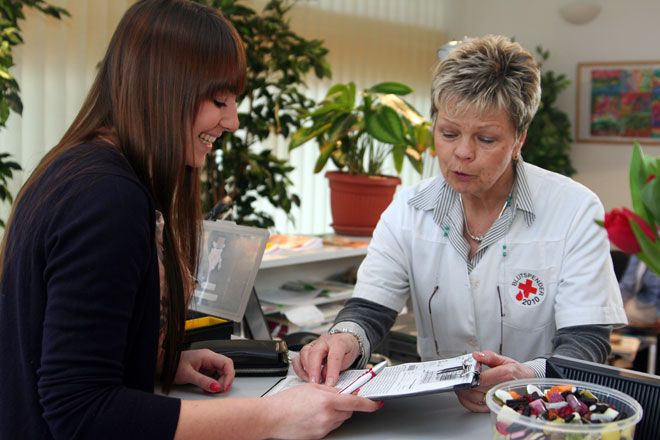 Foto: Eine junge Frau wird von einer DRK-Mitarbeiterin bei der Blutspende empfangen.